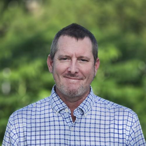 A photo of Doug Beer with the greenery on the background