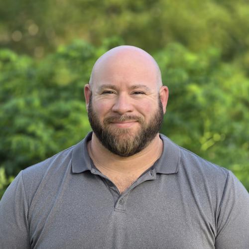 A photo of Dustin Miller with greenery on the background